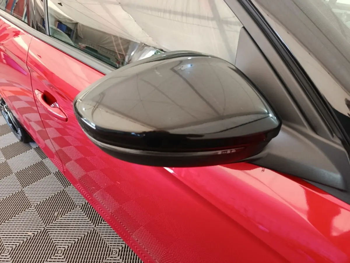 Gros plan sur le rétroviseur noir côté gauche d’une Opel Corsa rouge 2023, avec poignée de porte visible.