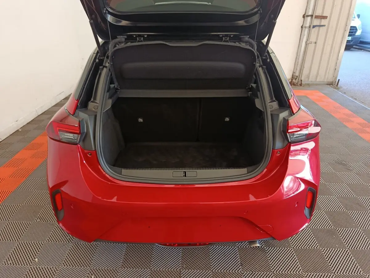 Vue arrière d'une Opel Corsa rouge 2023 avec coffre ouvert montrant l'espace de chargement vide.
