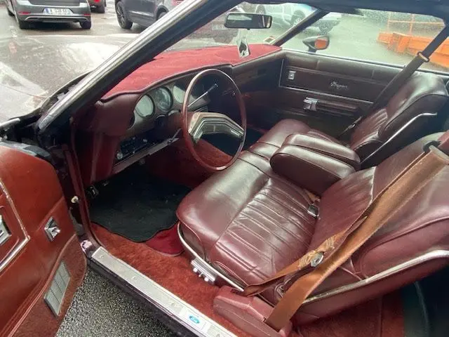 Intérieur bordeaux d'une Ford Aerostar Ranchero Squire 1979, vue côté conducteur avec tableau de bord et sièges en cuir.