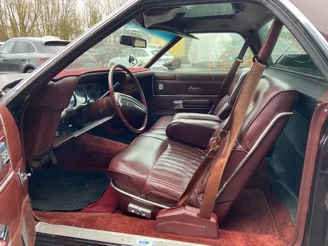 Intérieur bordeaux de la Ford Aerostar Ranchero Squire 1979, vue côté conducteur avec sièges en cuir et tableau de bord vintage.