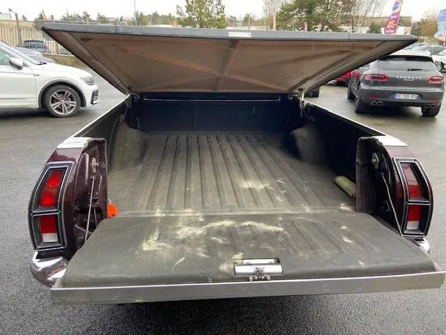 Vue arrière ouverte du Ford Aerostar Ranchero Squire bordeaux métal de 1979, mettant en valeur sa benne spacieuse et son hayon abaissé.