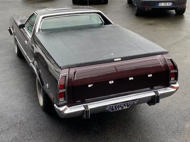 Vue arrière en léger 3/4 droit d'une Ford Aerostar Ranchero Squire bordeaux métallisé avec capote noire couvrant la benne.