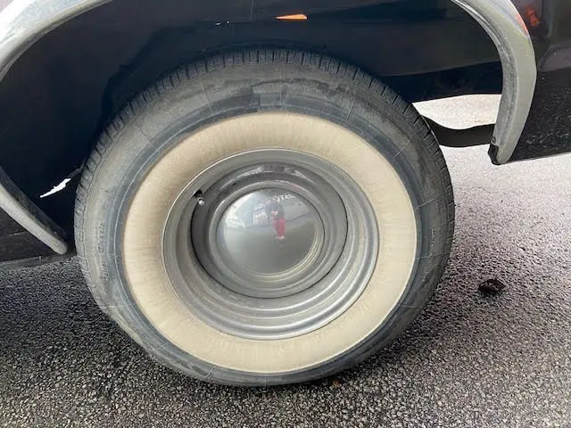 Gros plan sur la roue arrière droite d'une Ford Aerostar Ranchero Squire bordeaux métal de 1979 avec pneu à flanc blanc.