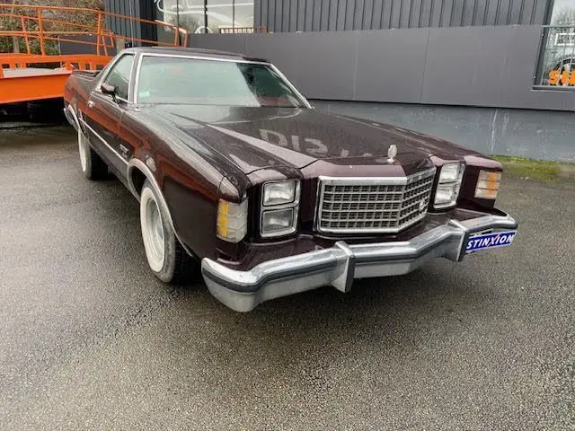Vue 3/4 avant gauche d'une Ford Aerostar Ranchero Squire bordeaux métal de 1979 avec calandre chromée et phares carrés.