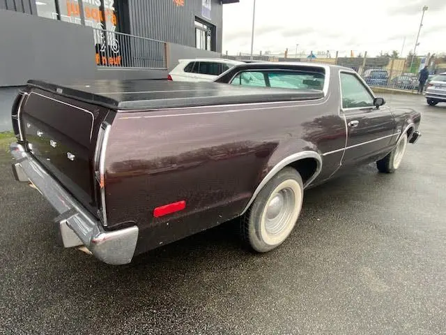Vue 3/4 arrière droite d'une Ford Aerostar Ranchero Squire bordeaux métal de 1979 avec benne couverte et jantes acier.