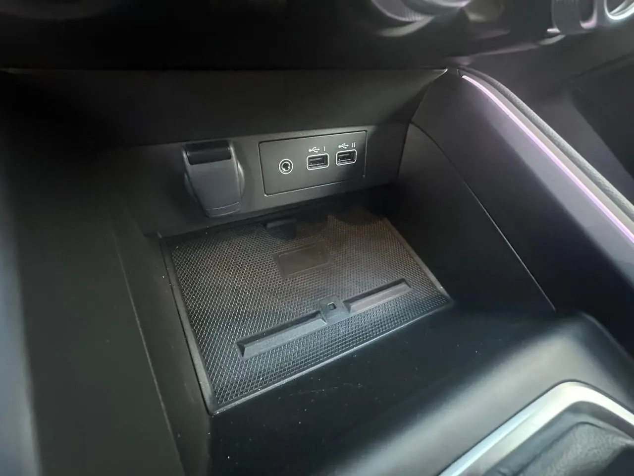 Prise USB double et prise jack dans la console centrale noire de la Renault Clio V Rouge Flamme, éclairage d'ambiance violet.