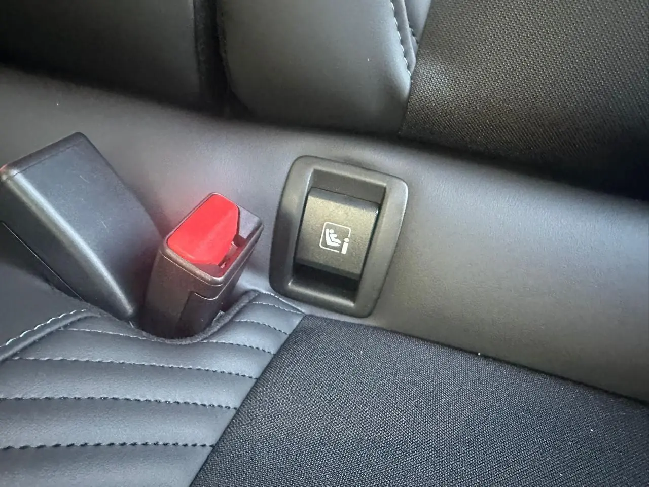 Gros plan sur la fixation ISOFIX et la boucle de ceinture rouge sur la banquette arrière noire de la Renault Clio V Esprit Alpine.