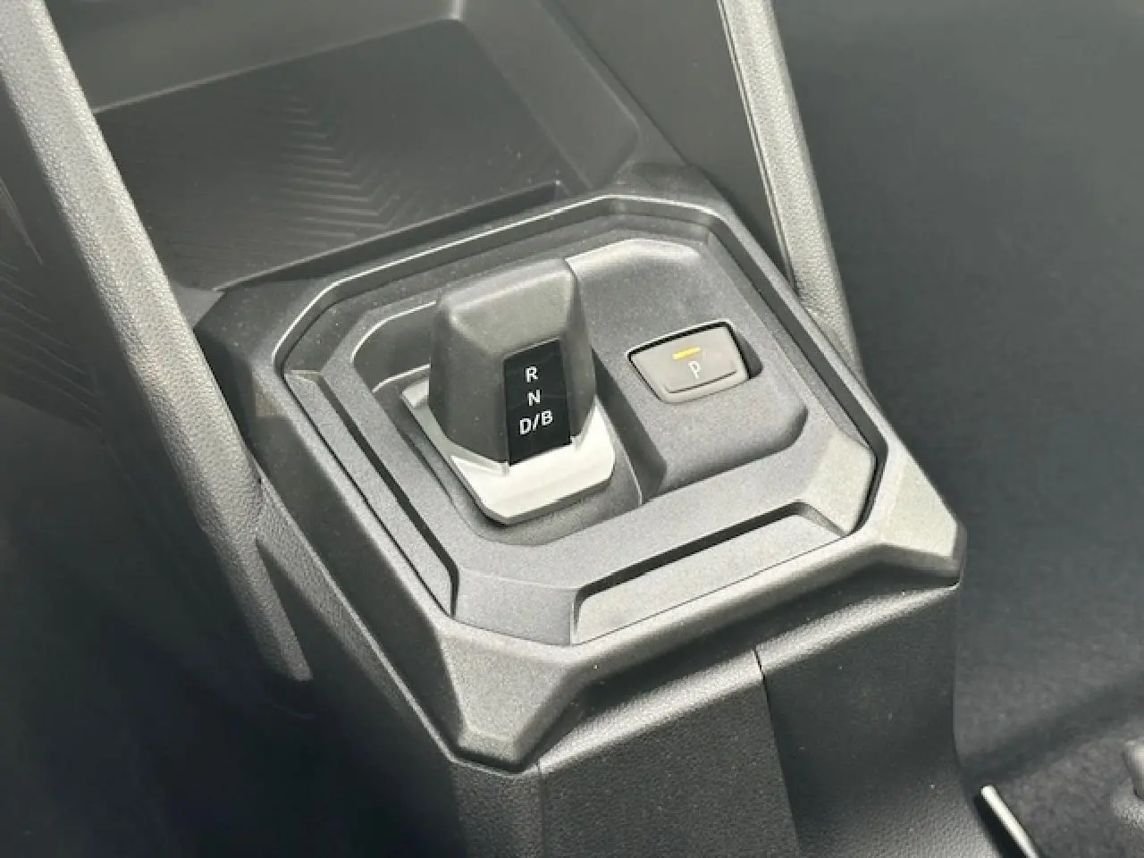 Gros plan sur le levier de vitesses automatique et bouton de parking du DACIA DUSTER III 1.6 Hybrid 2025, intérieur noir.