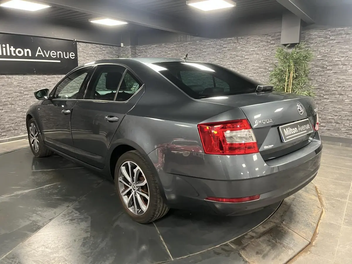 Vue 3/4 arrière droite d'une Skoda Octavia gris métallisé avec jantes alliage 17 pouces en intérieur showroom.