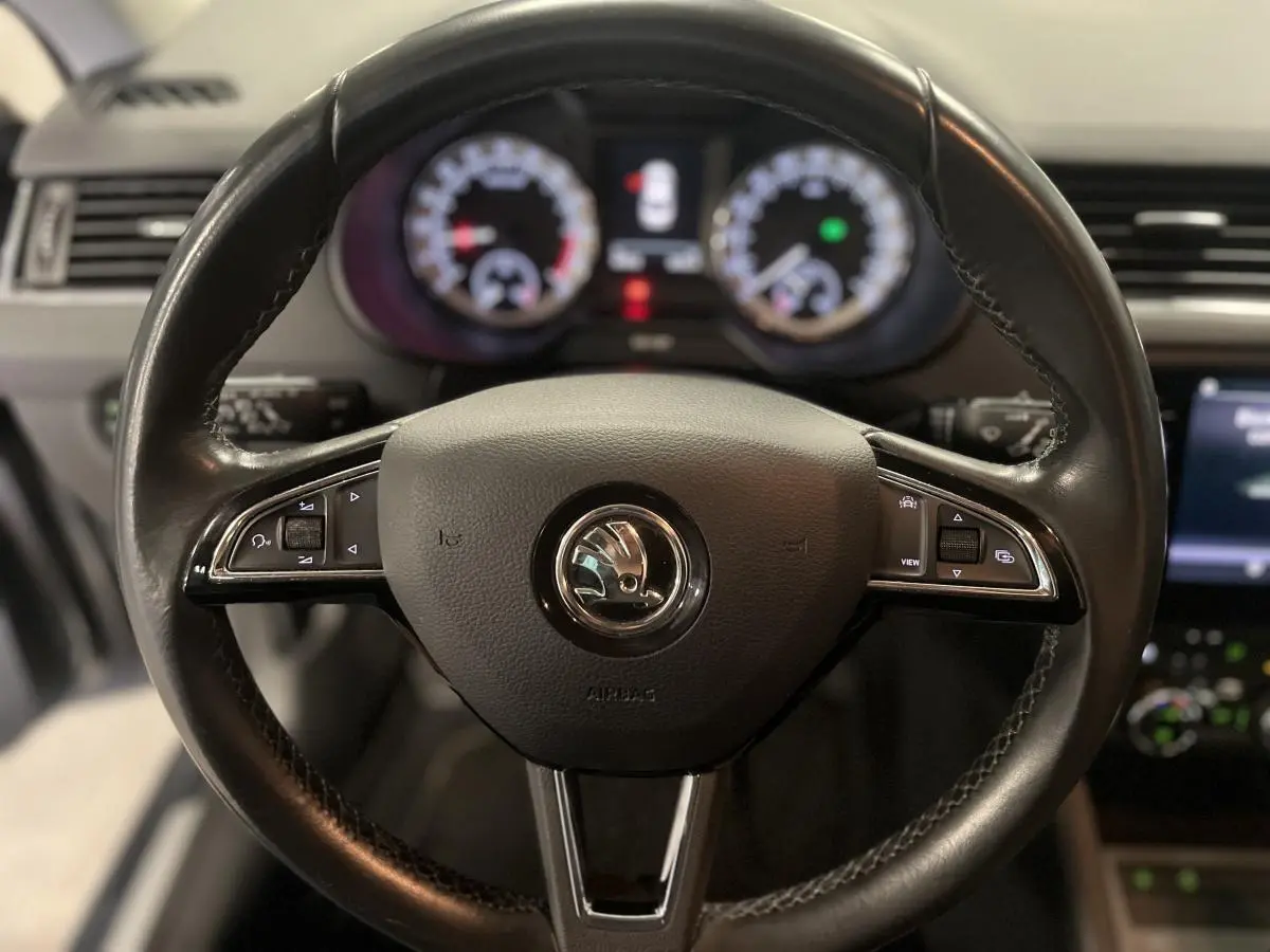 Volant cuir noir de Skoda Octavia 2020 avec commandes intégrées, tableau de bord numérique flou en arrière-plan.