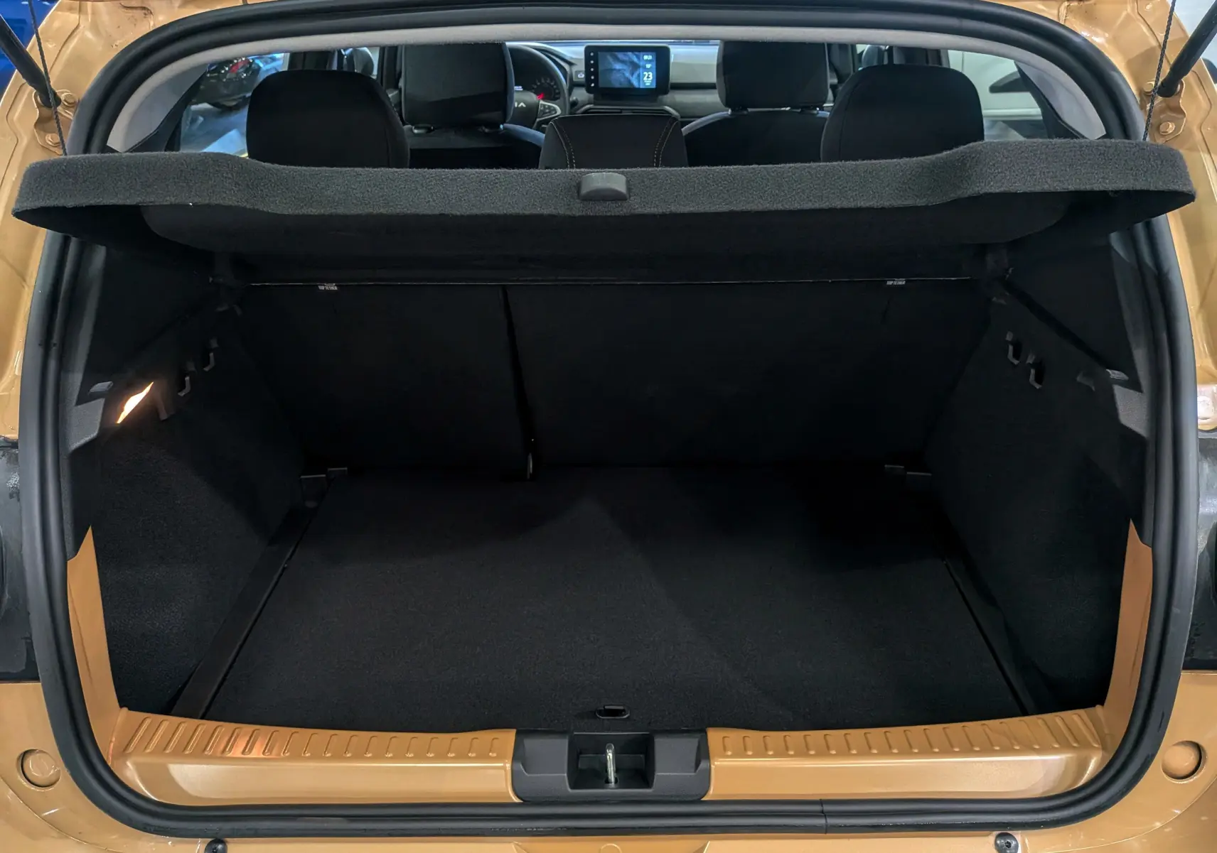 Coffre ouvert vu de l'arrière d'une Dacia Sandero Stepway beige Safari 2025, intérieur noir et tablette arrière relevée.