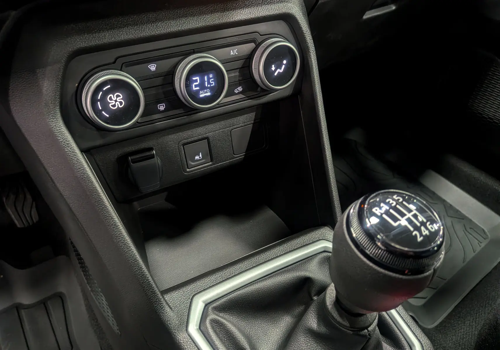Gros plan sur la console centrale de la Dacia Sandero Stepway beige Safari 2025, avec la commande de climatisation et le levier de vitesses manuel.