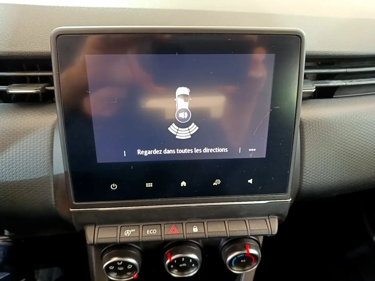 Écran tactile central affichant l'alerte de capteurs de recul dans l'habitacle d'une Renault Clio Business blanc.