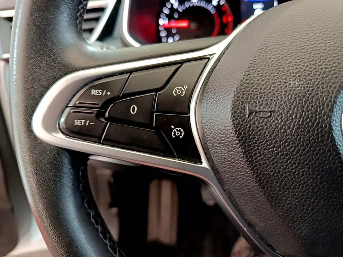 Gros plan sur le volant cuir noir de la Renault Clio Business, montrant les commandes du régulateur de vitesse à gauche.