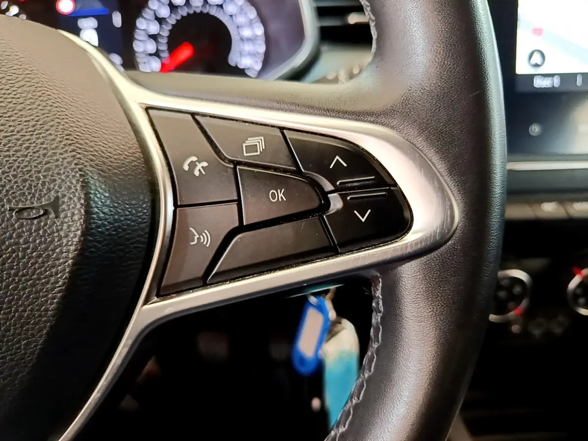 Gros plan sur les commandes multifonctions du volant en cuir noir de la Renault Clio Business Blue dCi 85 blanche de 2020.