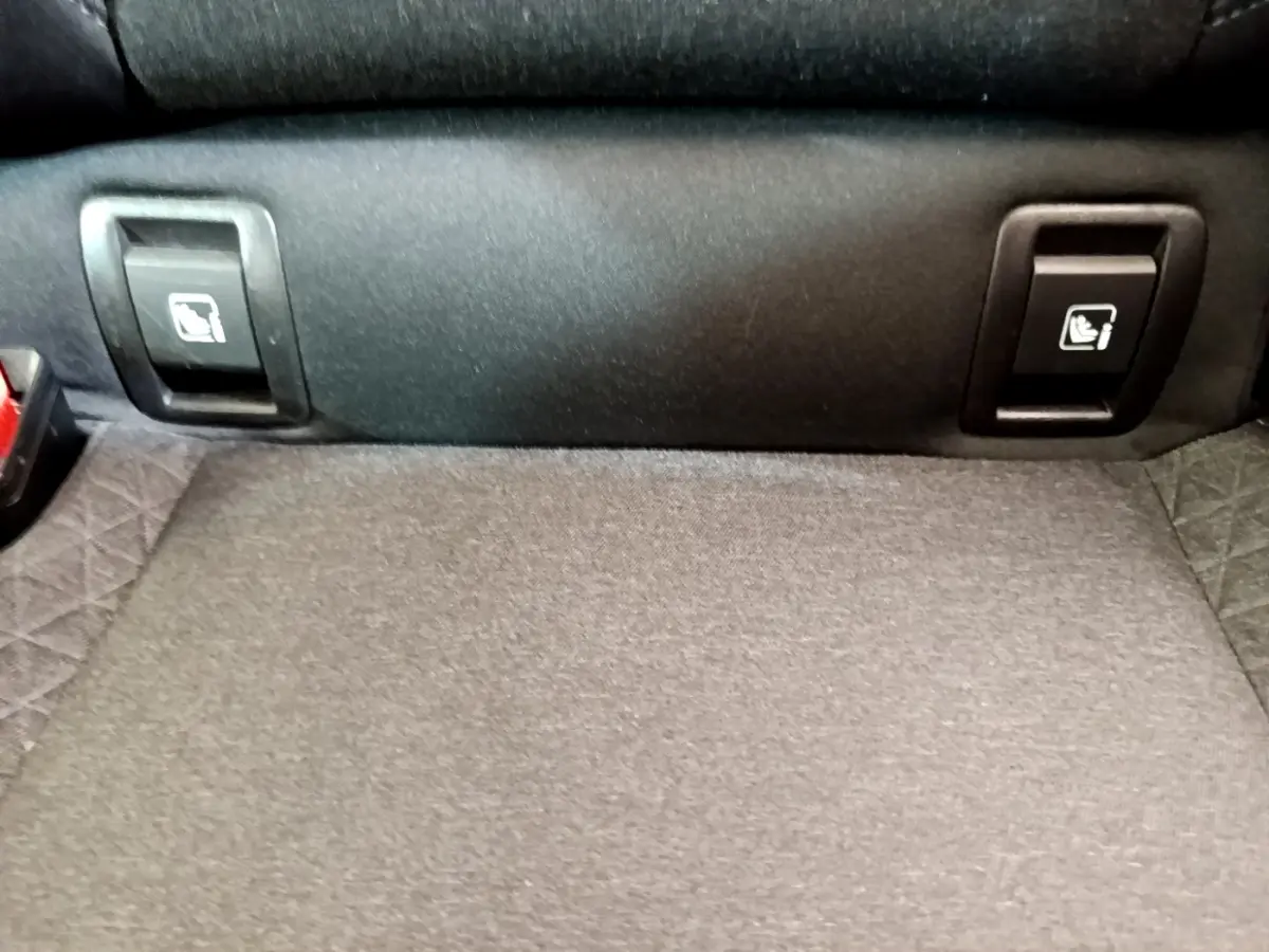 Gros plan sur la banquette arrière et les commandes d'abaissement des sièges dans le coffre de la Renault Clio Business blanche.