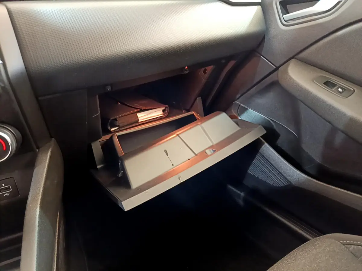 Gant de boîte à gants ouvert côté passager dans l'habitacle noir de la Renault Clio Business Blue dCi 85 blanche.