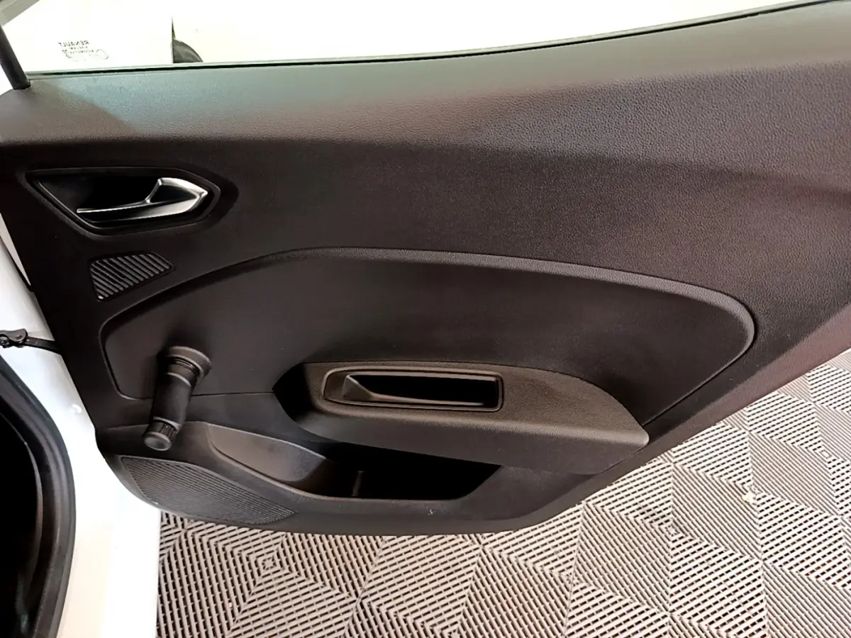 Vue intérieure du panneau de porte côté gauche de la Renault Clio Business blanc, avec manivelle de vitre manuelle.