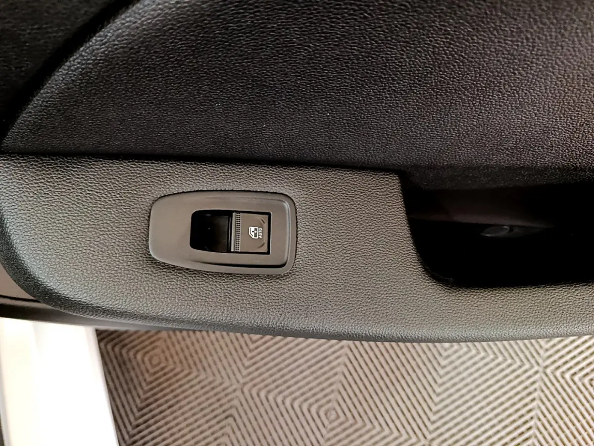 Bouton de commande de lève-vitre sur la porte intérieure noire côté conducteur d'une Renault Clio Business 2020 blanche.