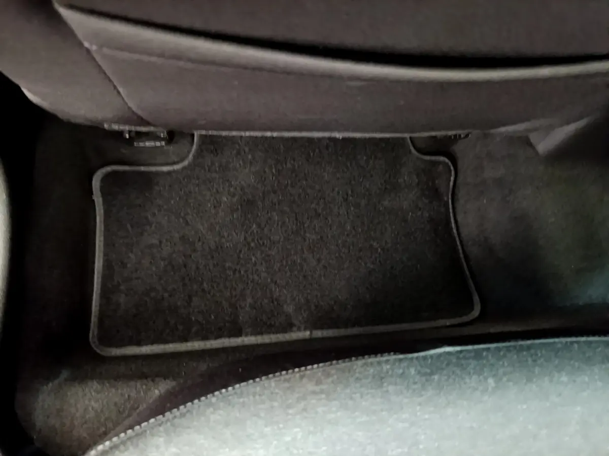 Vue rapprochée du tapis de sol noir côté passager arrière d'une Renault Clio Business Blue dCi 85 blanche de 2020.