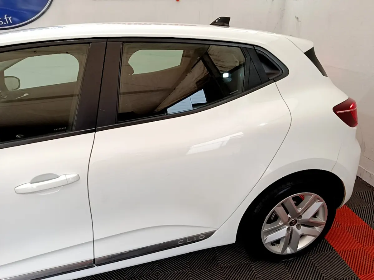 Vue de profil côté gauche d'une Renault Clio blanche avec jantes alliage et poignées de porte intégrées.