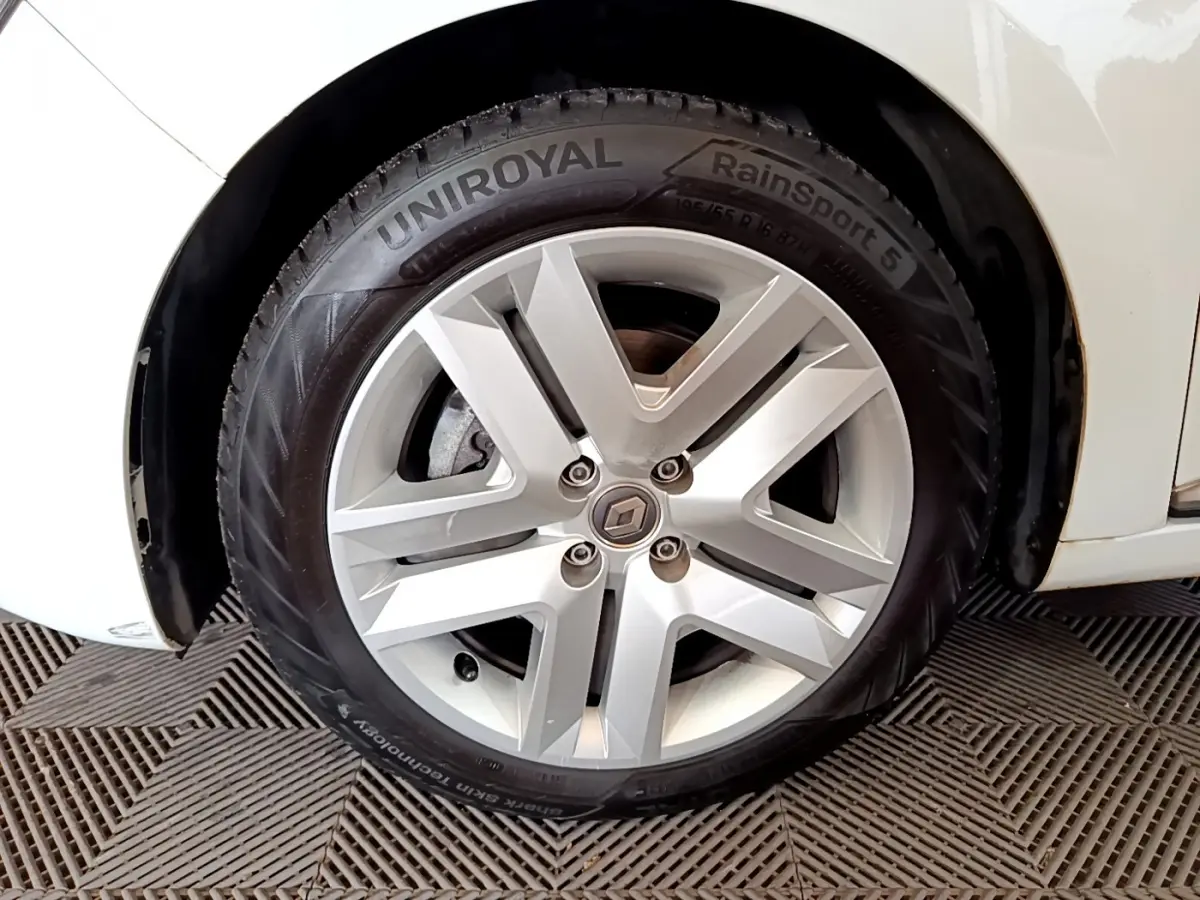 Gros plan sur la roue avant droite blanche d'une Renault Clio Business Blue dCi 85 avec jante alliage et pneu Uniroyal.