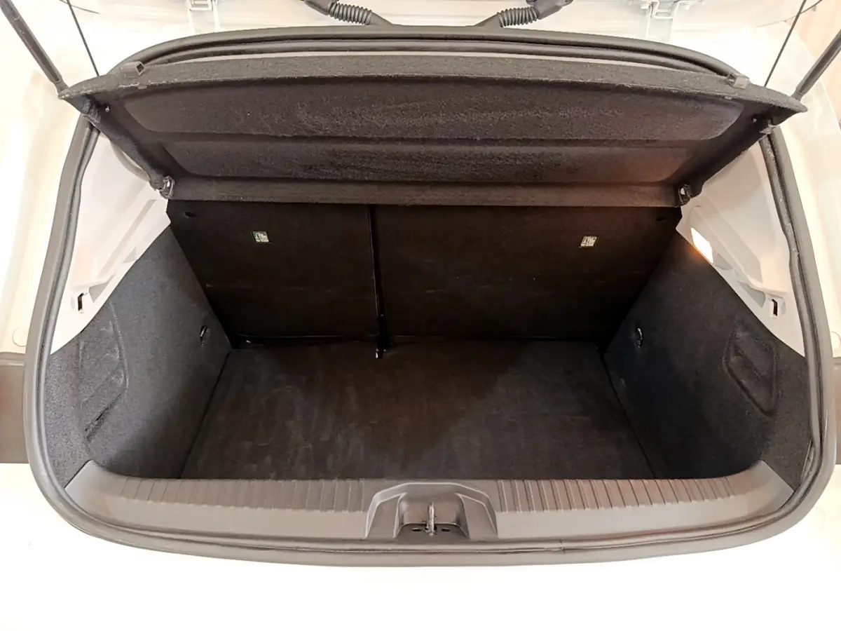 Coffre ouvert vu de l'arrière d'une Renault Clio Business Blue dCi 85 blanche, intérieur noir et espace de rangement visible.