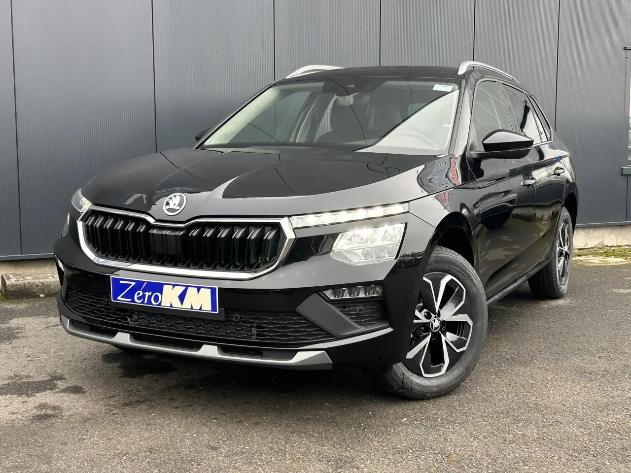 Vue 3/4 avant droite d'un Skoda Kamiq noir Magic avec jantes alliage et calandre chromée brillante.