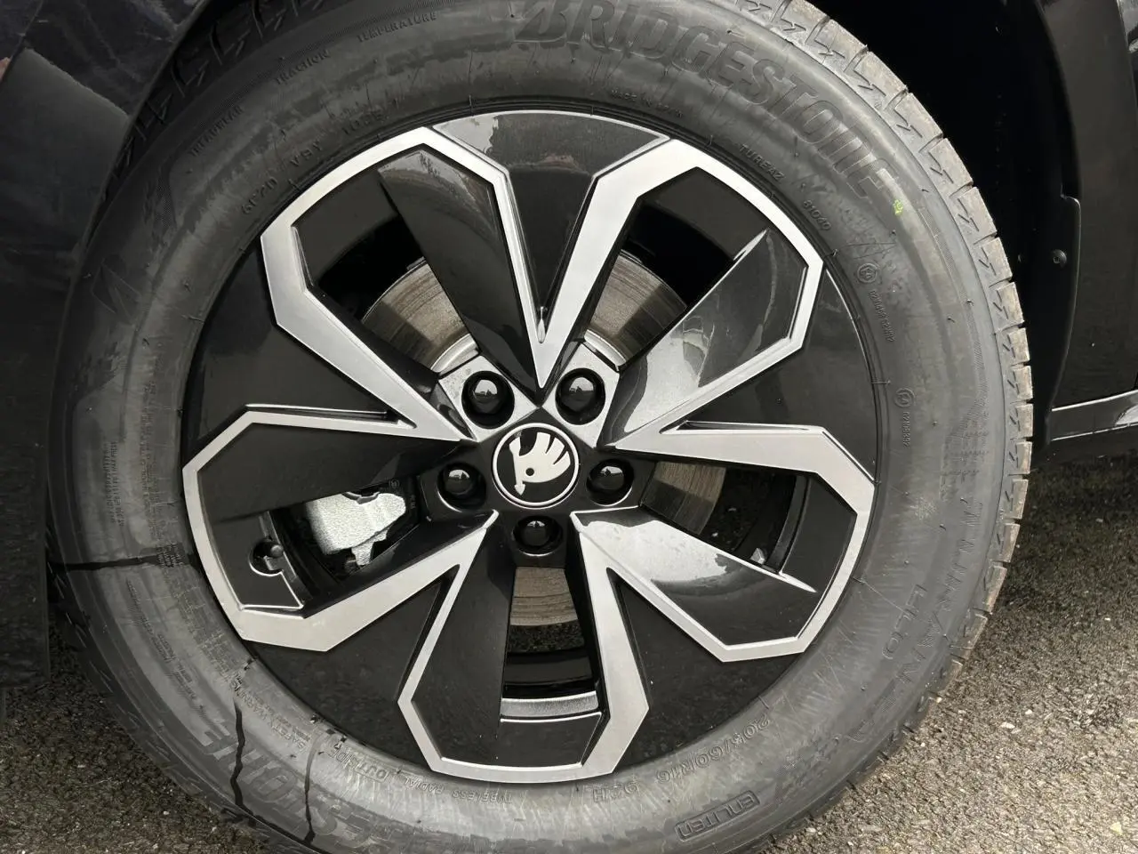 Gros plan sur la jante alliage noire et argentée du Skoda Kamiq noir Magic, mettant en valeur le logo central.