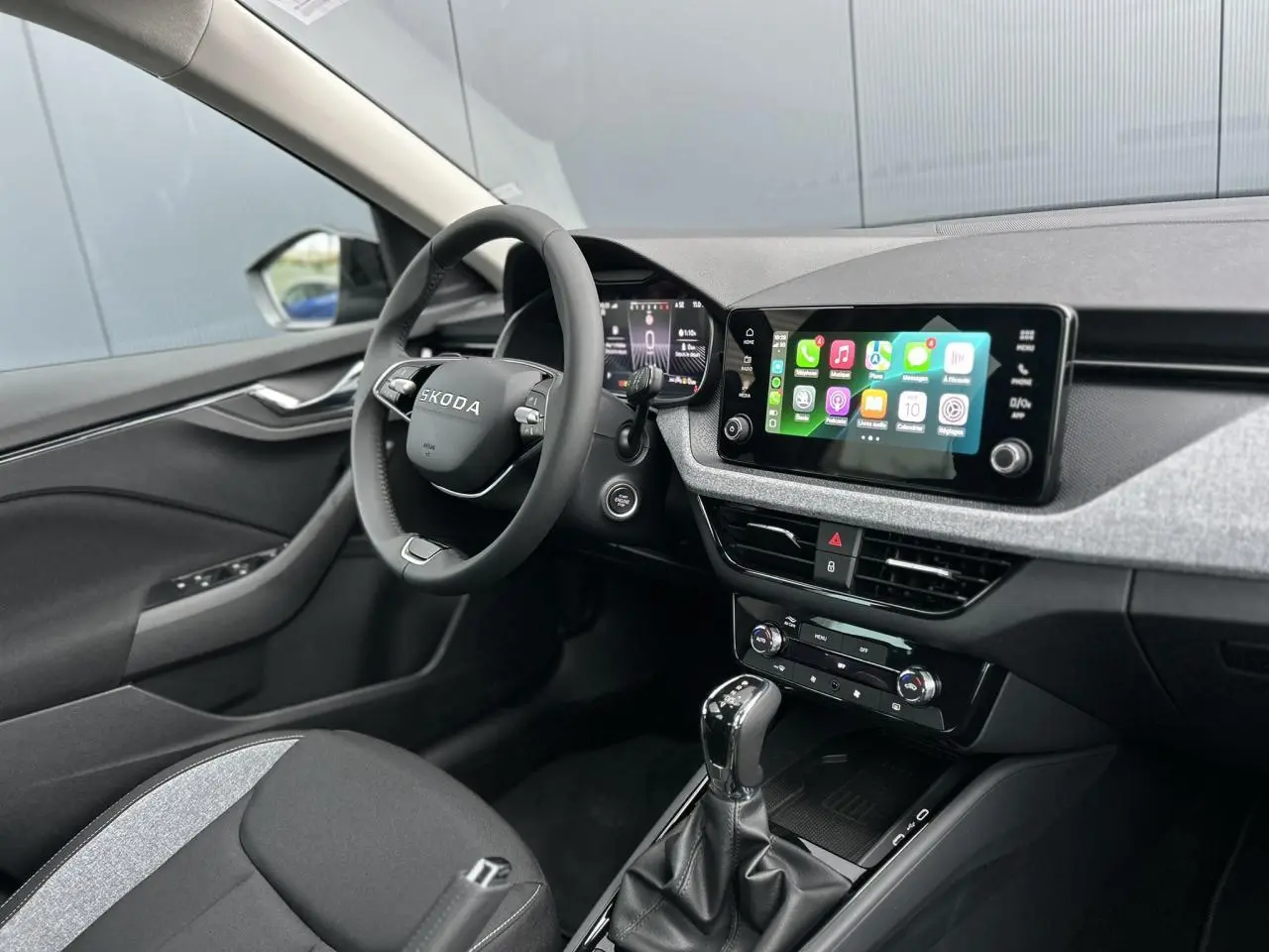 Vue intérieure côté conducteur du Skoda Kamiq 2025 noir Magic, avec écran tactile Apple Car Play et volant multifonctions cuir.