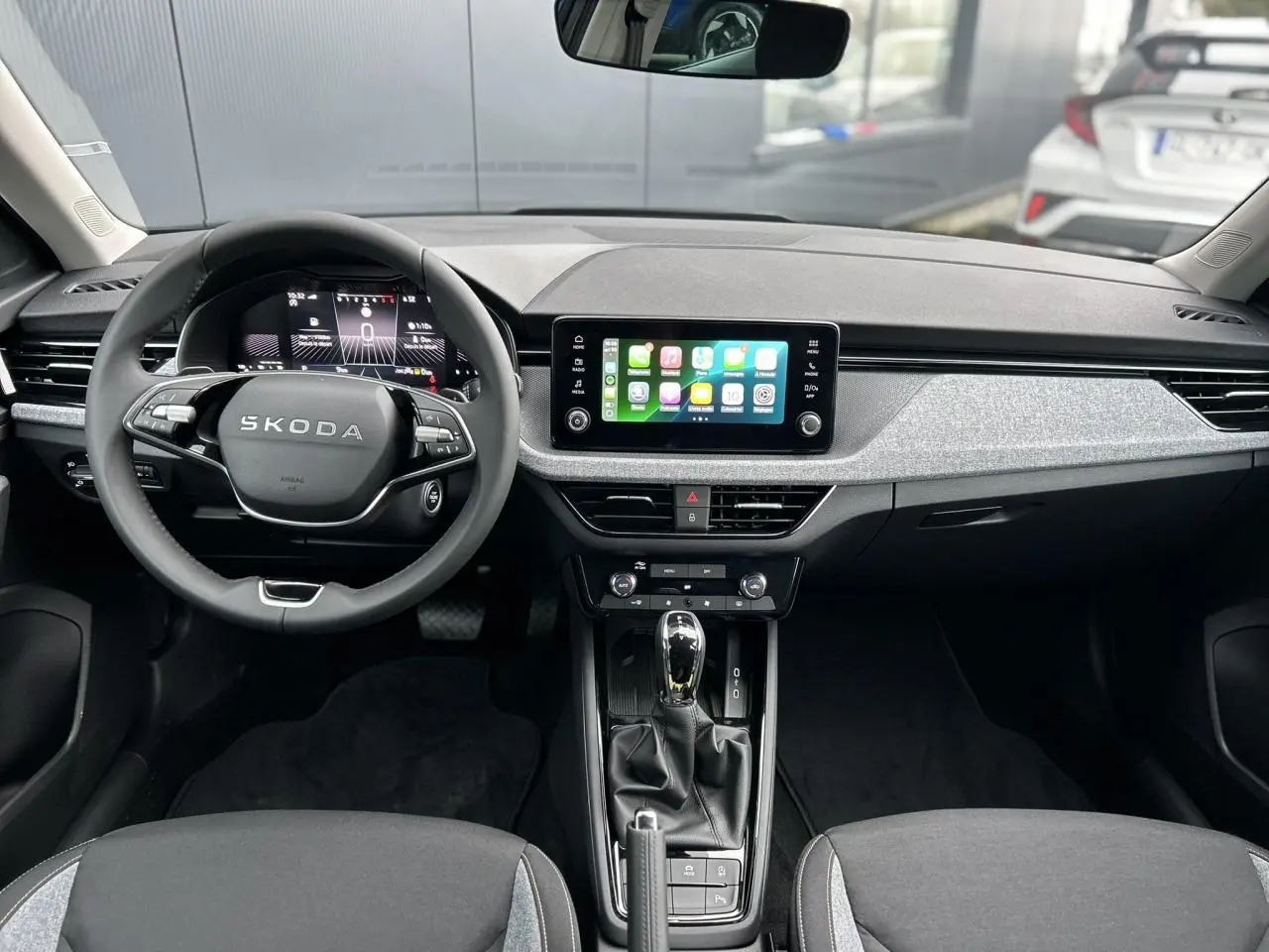 Vue intérieure frontale du tableau de bord du Skoda Kamiq 2025 avec écran tactile Apple Car Play et volant multifonctions.