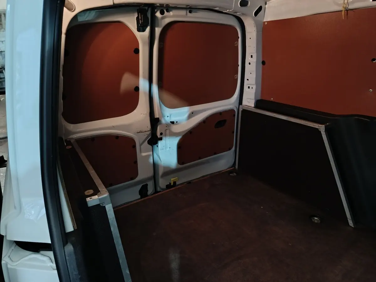 Intérieur de la zone de chargement du Citroën Berlingo blanc, vue arrière avec cloison pleine et revêtement marron.