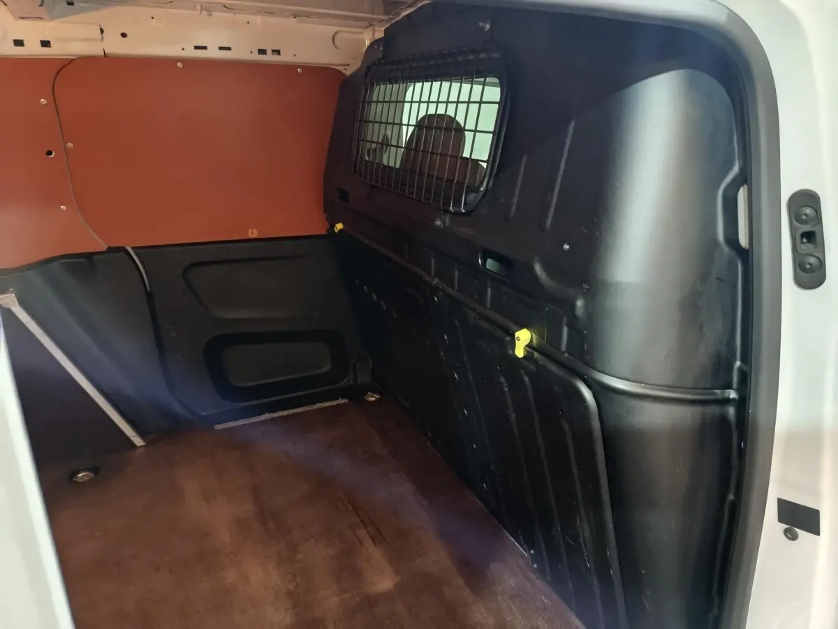 Vue intérieure du compartiment de chargement du Citroën Berlingo blanc avec cloison pleine et revêtement marron au sol.