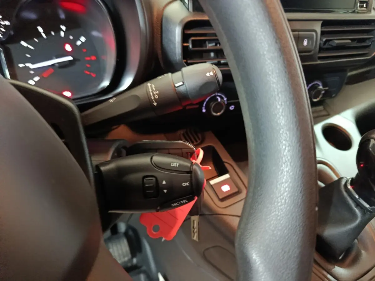 Gros plan sur le volant et commandes au volant du Citroën Berlingo blanc, avec tableau de bord et levier de vitesses visibles.