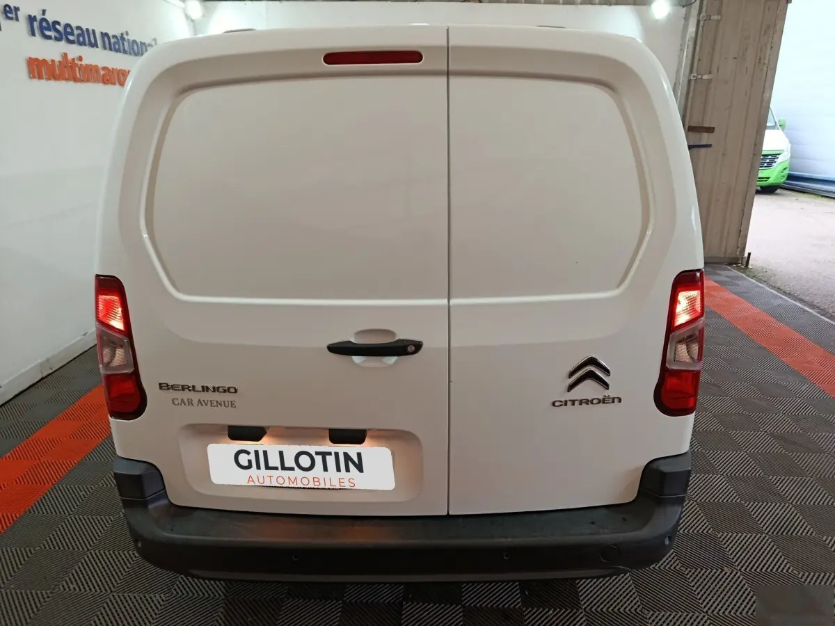 Vue arrière du Citroën Berlingo blanc 2021 avec portes battantes et feux arrière allumés dans un garage.