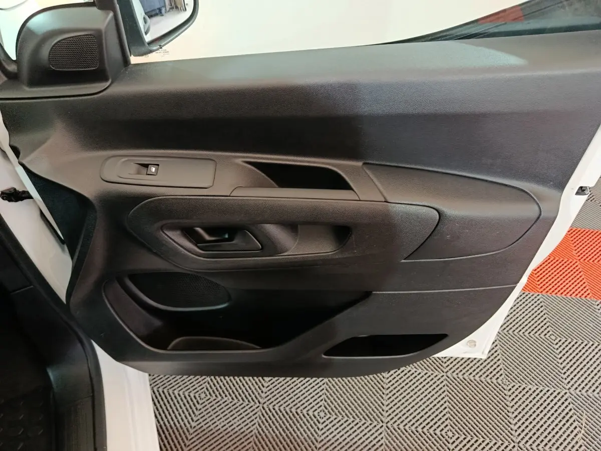 Vue rapprochée de la porte avant gauche noire du Citroën Berlingo blanc, montrant la poignée et les commandes de vitre.