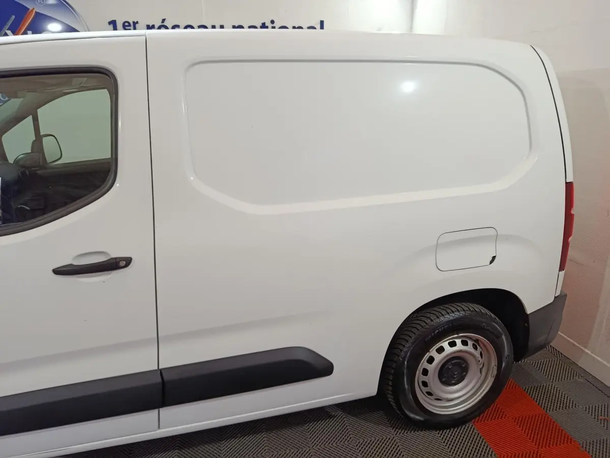 Vue de profil côté droit d'un utilitaire Citroën Berlingo blanc avec porte latérale pleine et jante acier.