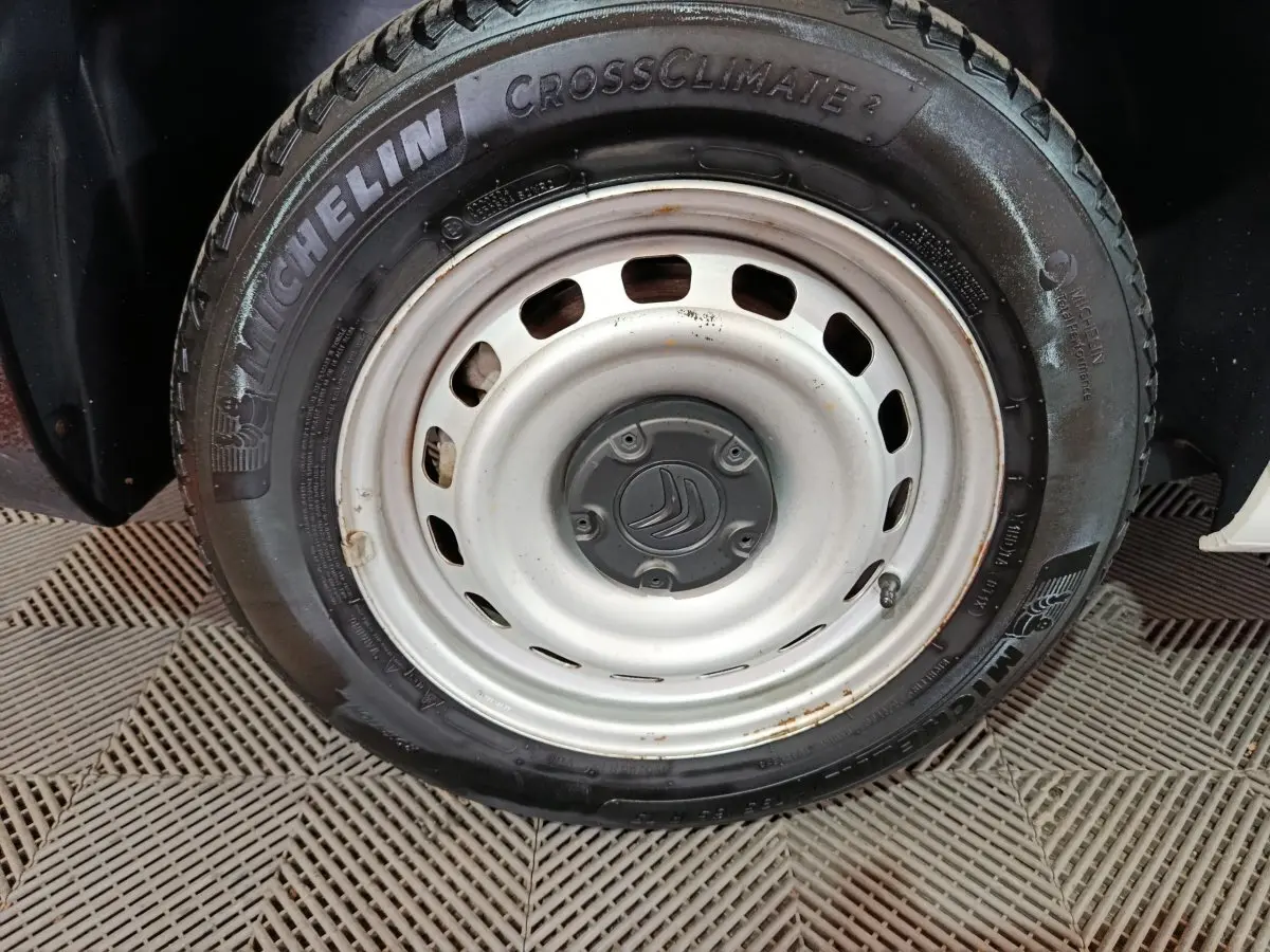 Gros plan sur la roue acier blanche avec logo Citroën et pneu Michelin CrossClimate sur Berlingo blanc.