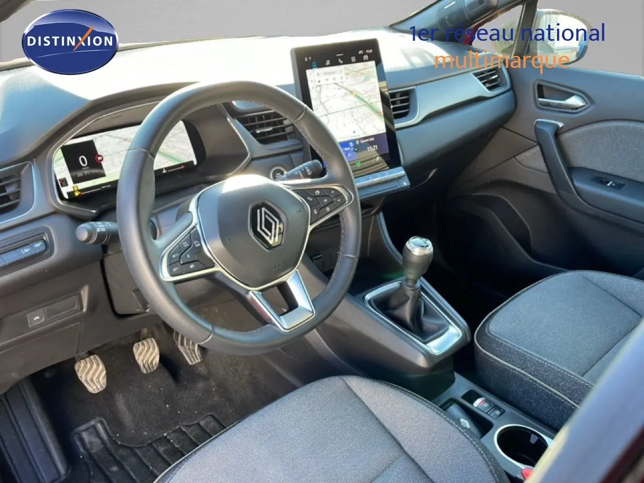 Intérieur du Renault Captur 2025, vue côté conducteur, volant cuir, écran tactile vertical et boîte manuelle visible.