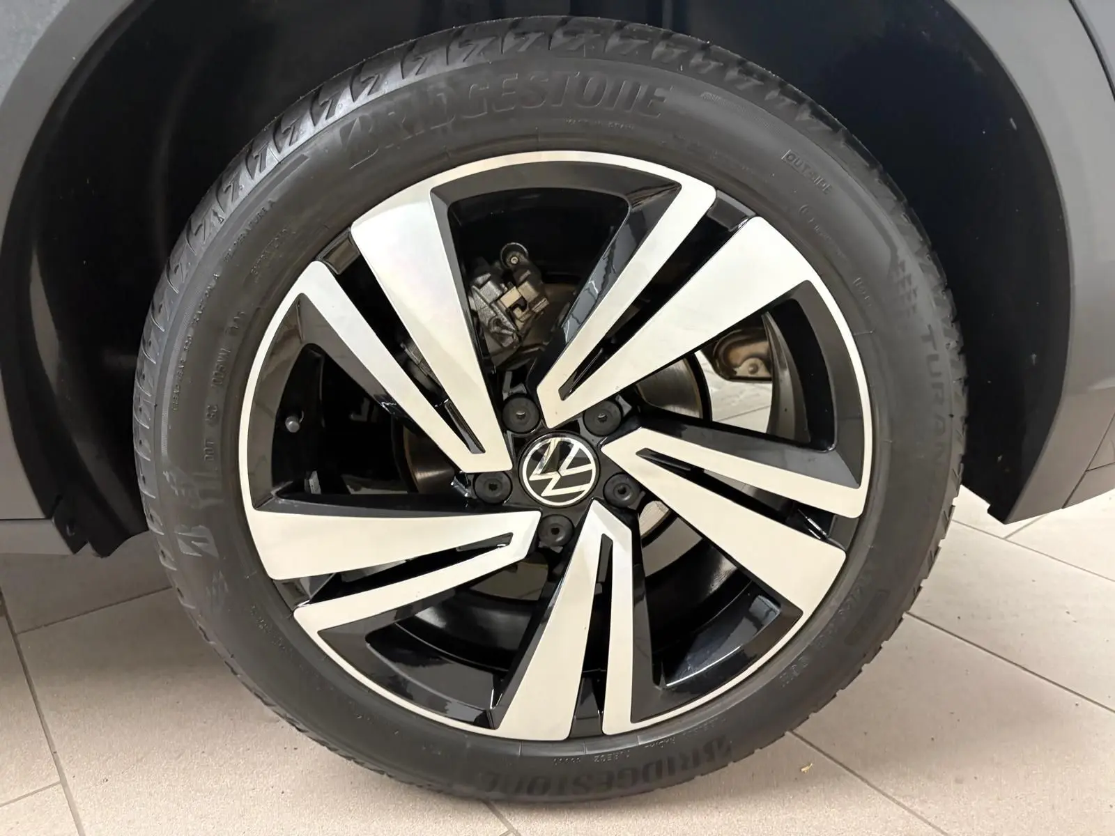 Gros plan sur la jante noire et argentée du Volkswagen T-Roc 1.5 TSI 150 DSG7 R-Line Edition 2025 en noir intense.