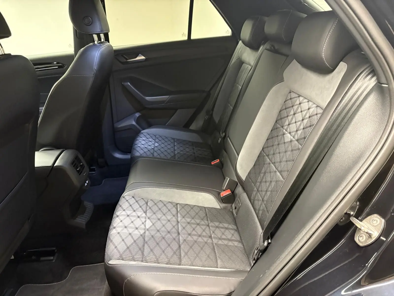 Vue intérieure côté droit des sièges arrière en tissu et cuir noir avec surpiqûres blanches du Volkswagen T-Roc 2025.
