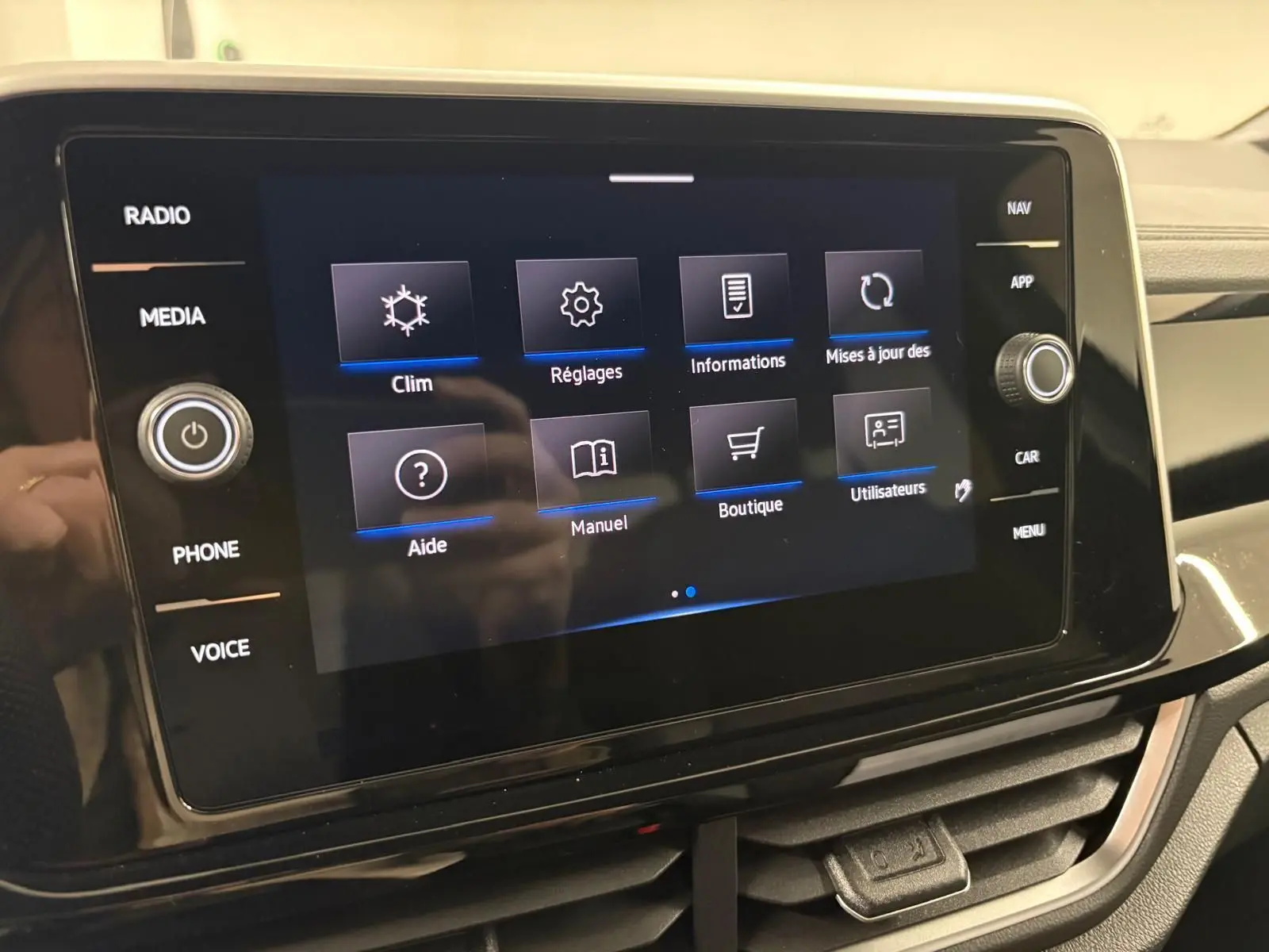 Écran tactile central du Volkswagen T-Roc 2025 affichant le menu principal avec options clim, réglages et boutique.
