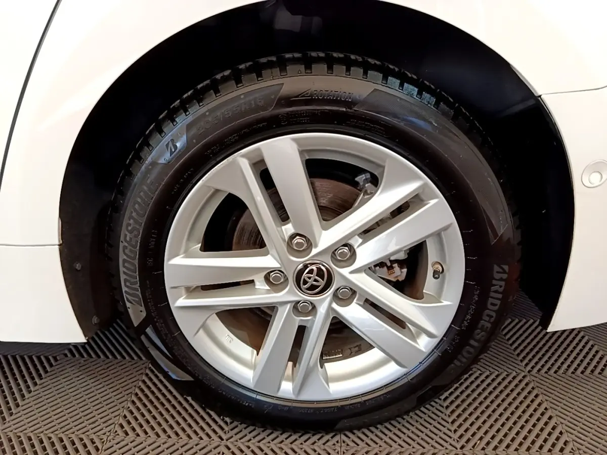 Gros plan sur la roue avant droite blanche d'une Toyota Corolla hybride 2022 avec jante alliage et logo Toyota central.