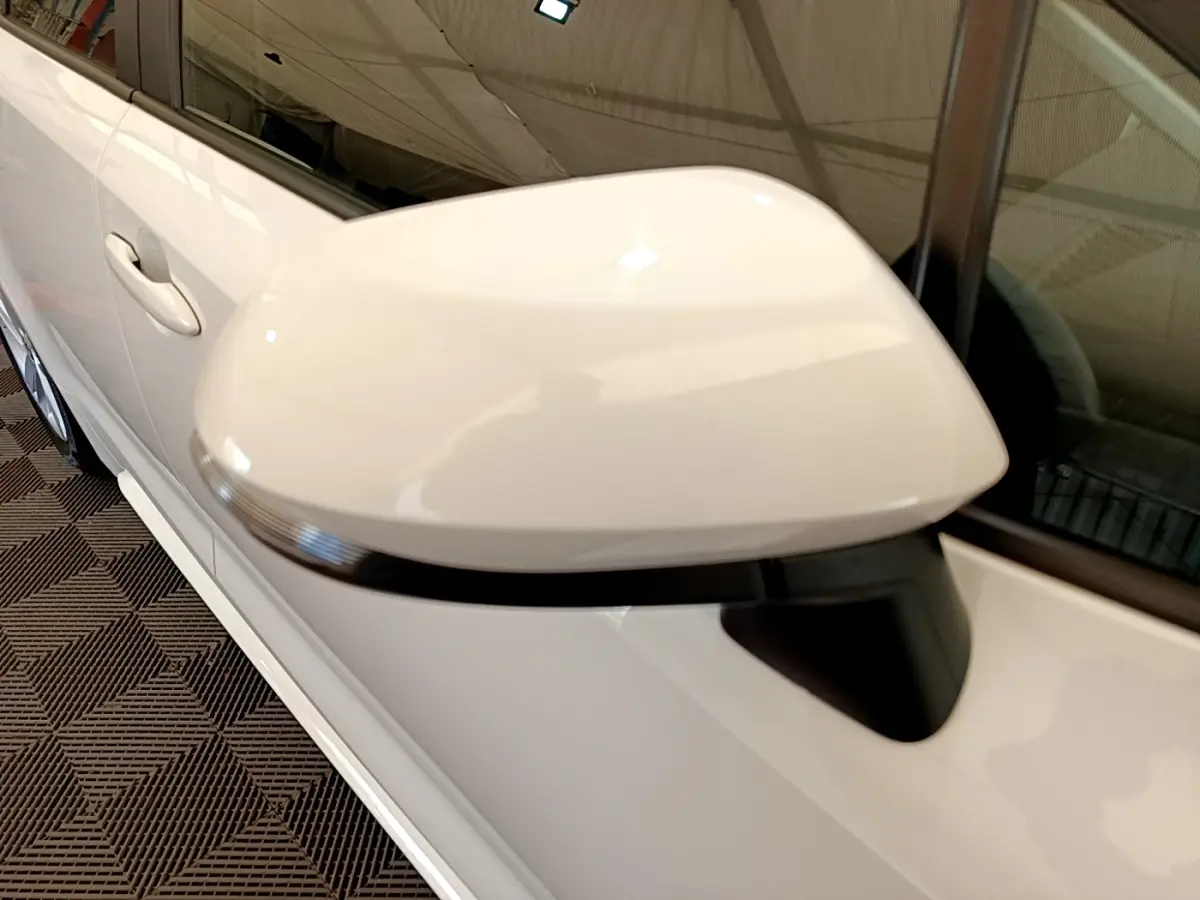 Gros plan sur le rétroviseur droit blanc de la Toyota Corolla hybride 2022, avec la portière et la poignée visibles.