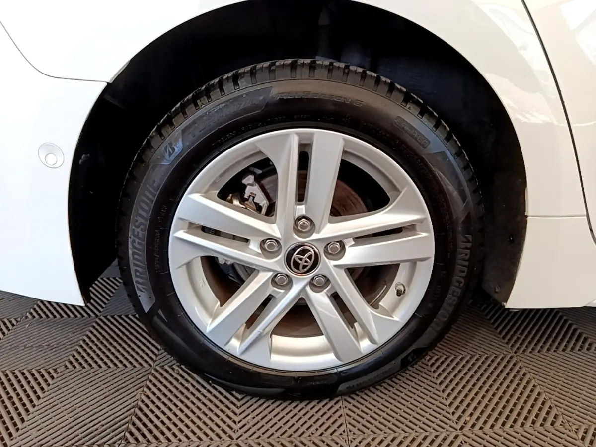 Gros plan sur la roue avant droite d'une Toyota Corolla blanche, mettant en valeur la jante alliage à cinq branches.