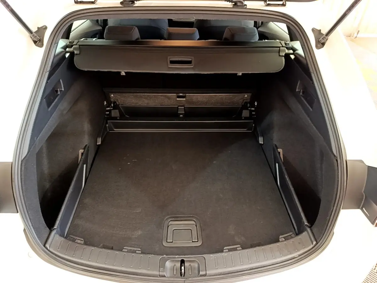 Coffre ouvert de la Toyota Corolla hybride blanche 2022, vue arrière montrant l’espace de chargement vide et la tablette cache-bagages.