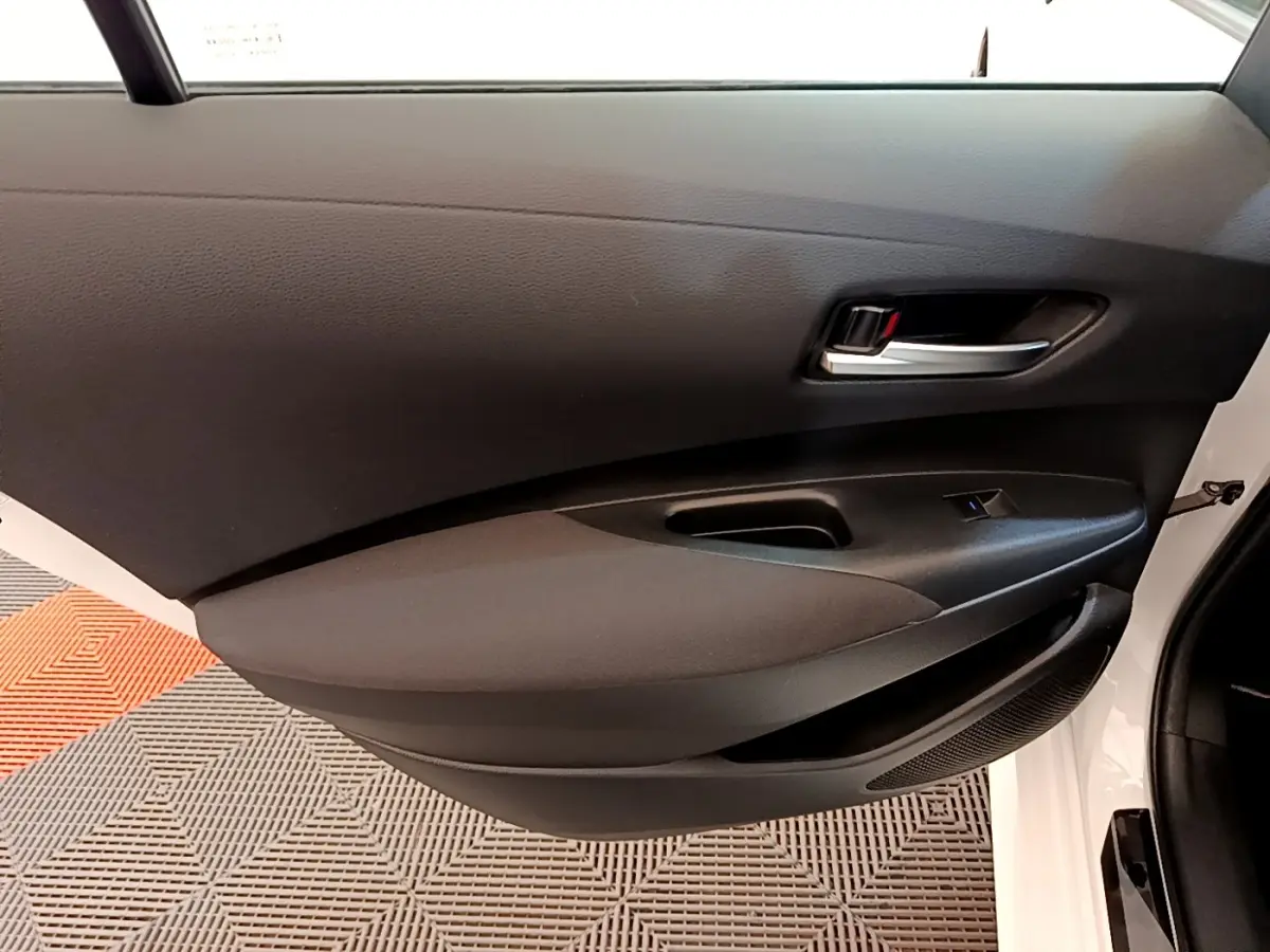 Vue intérieure du panneau de porte avant gauche noir de la Toyota Corolla Hybride blanche 2022.