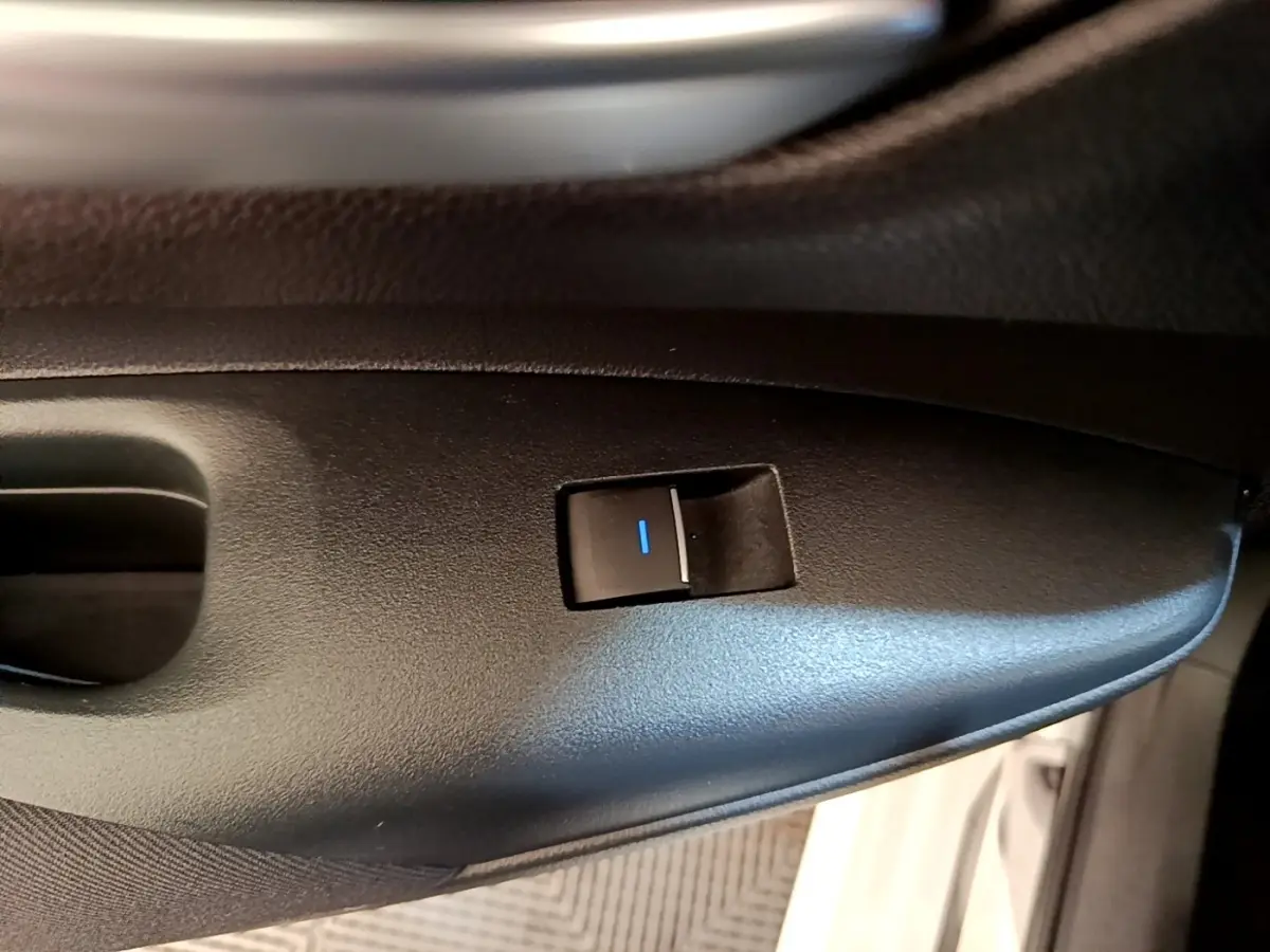 Gros plan sur l'interrupteur de verrouillage des portes côté conducteur d'une Toyota Corolla blanche hybride 2022.