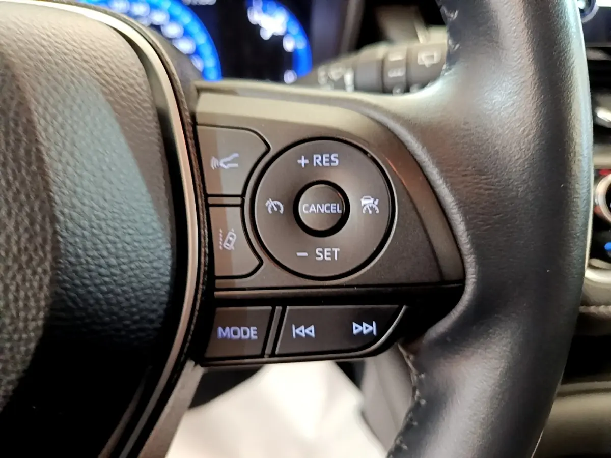 Gros plan sur les commandes multifonctions du volant cuir noir de la Toyota Corolla Hybride 2022.