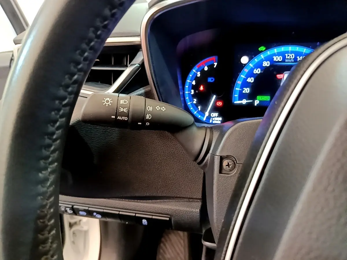 Vue rapprochée du tableau de bord et du volant cuir de la Toyota Corolla hybride 2022 avec affichage numérique bleu.